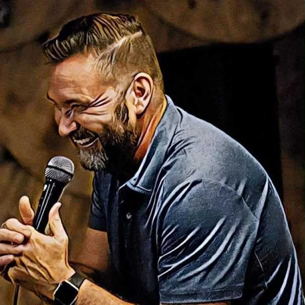 Bill Bushart laughing into a microphone on stage